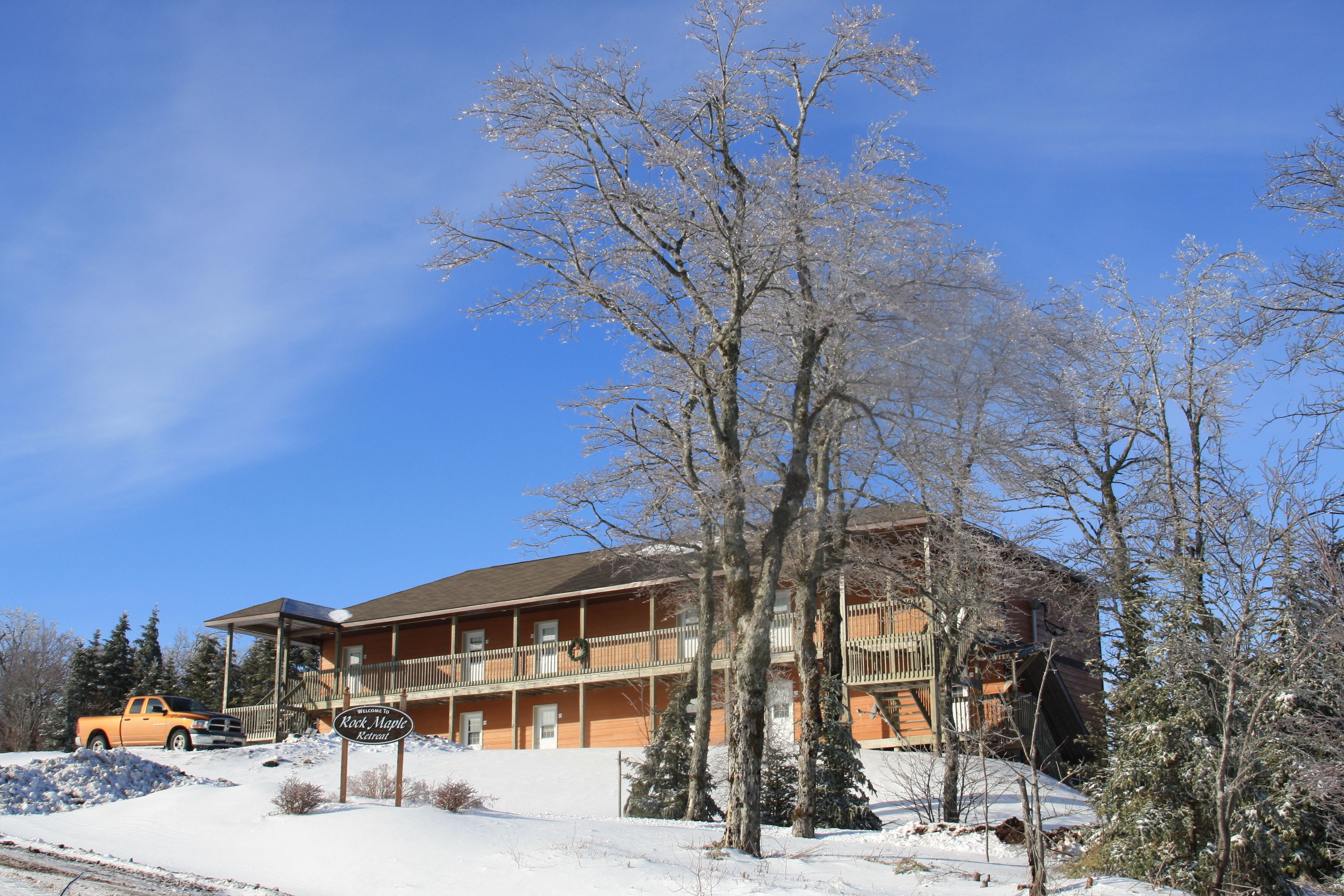 A lodge with a balcony, a sign, and a snow-covered landscape.