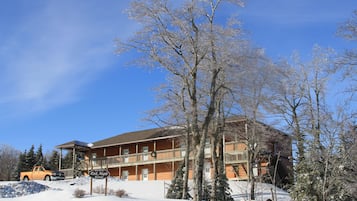 A lodge with a balcony, a sign, and a snow-covered landscape.