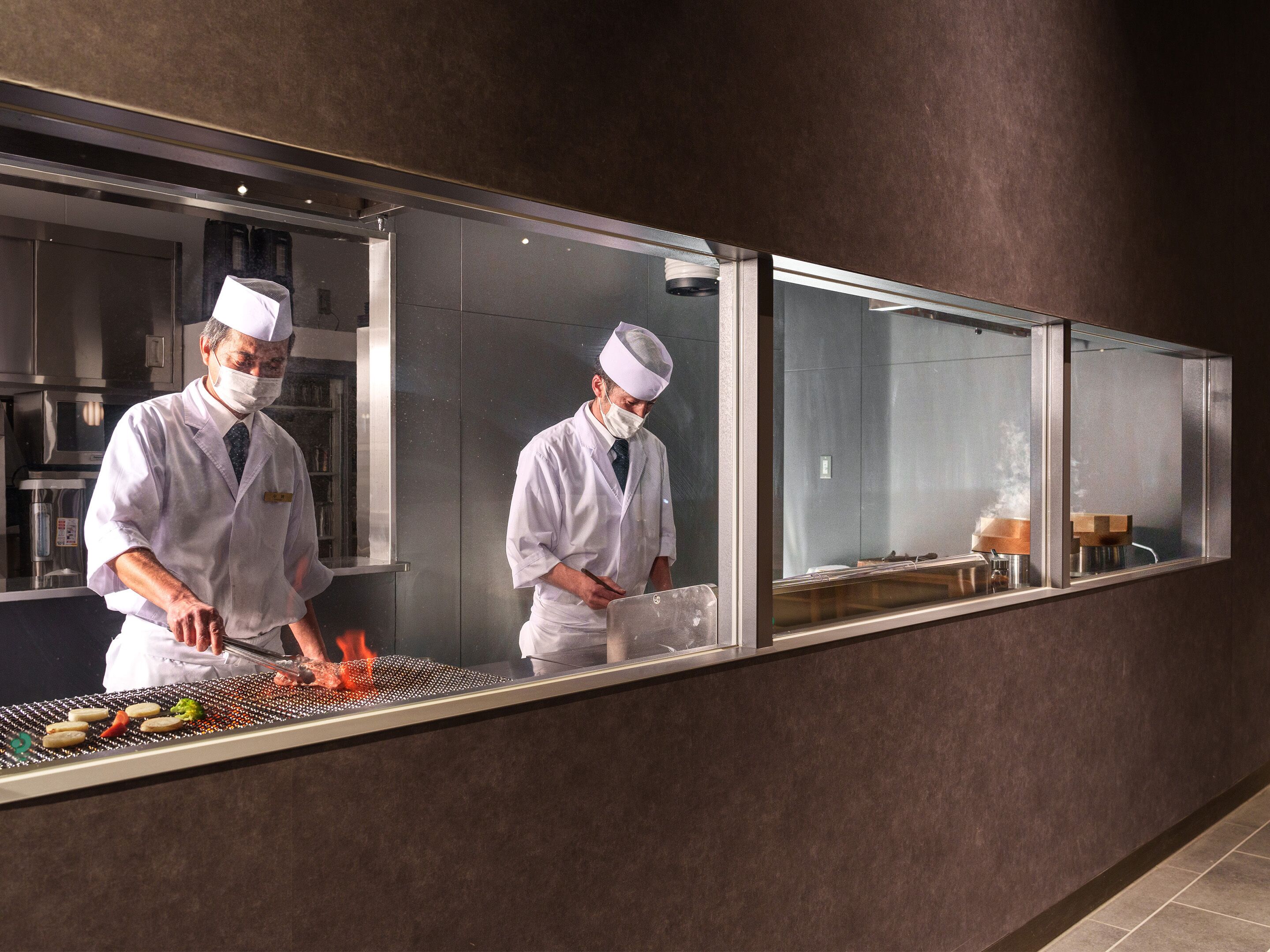 Un chef préparant des plats devant un comptoir, avec une cuisine moderne en arrière-plan.