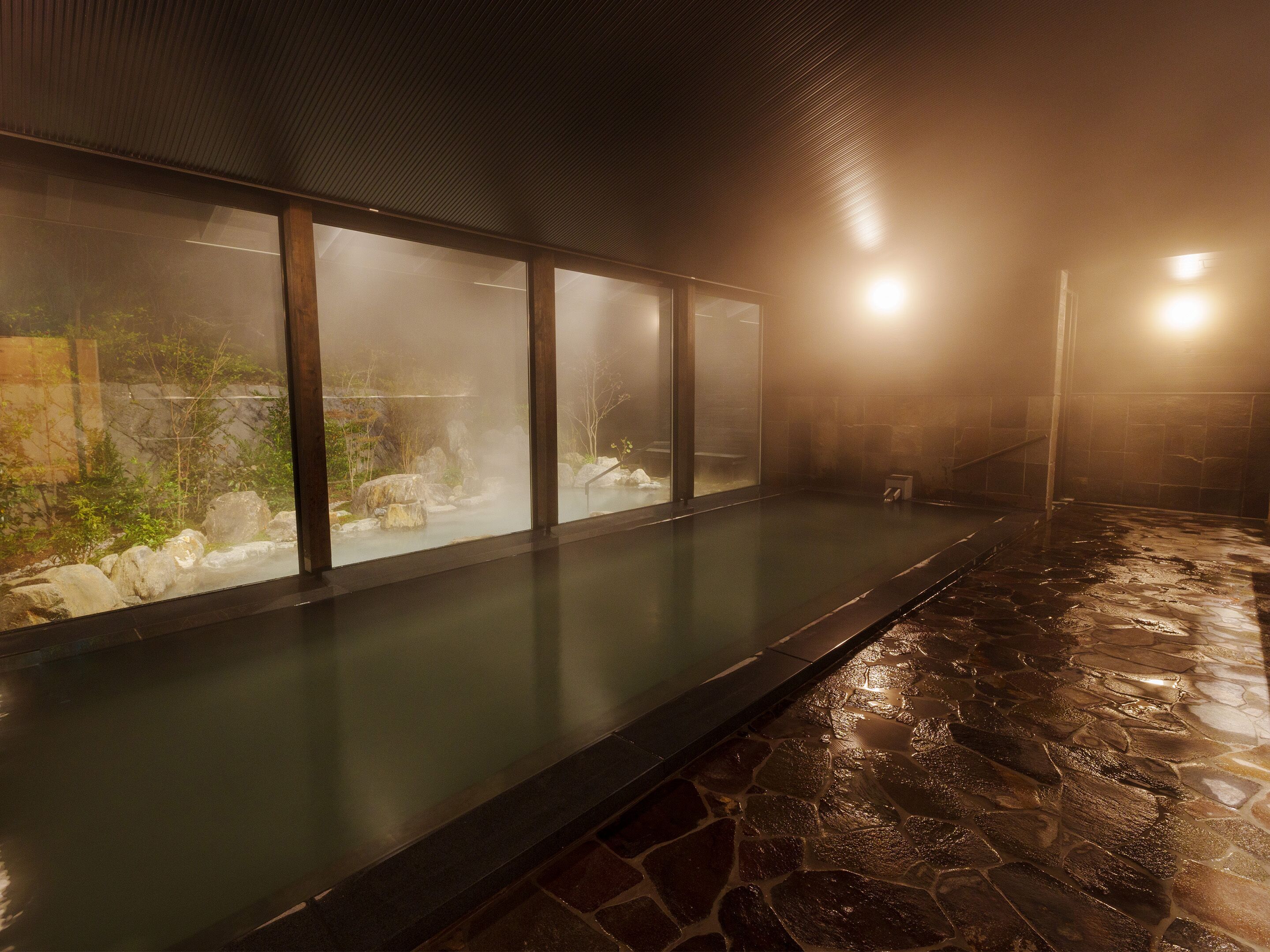 A stone-floored indoor pool area with glass walls.