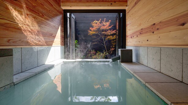 A modern indoor pool with a clear view of the outdoors, surrounded by wooden walls and a tiled floor. - Unzen Miyazaki Ryokan (Unzen)
