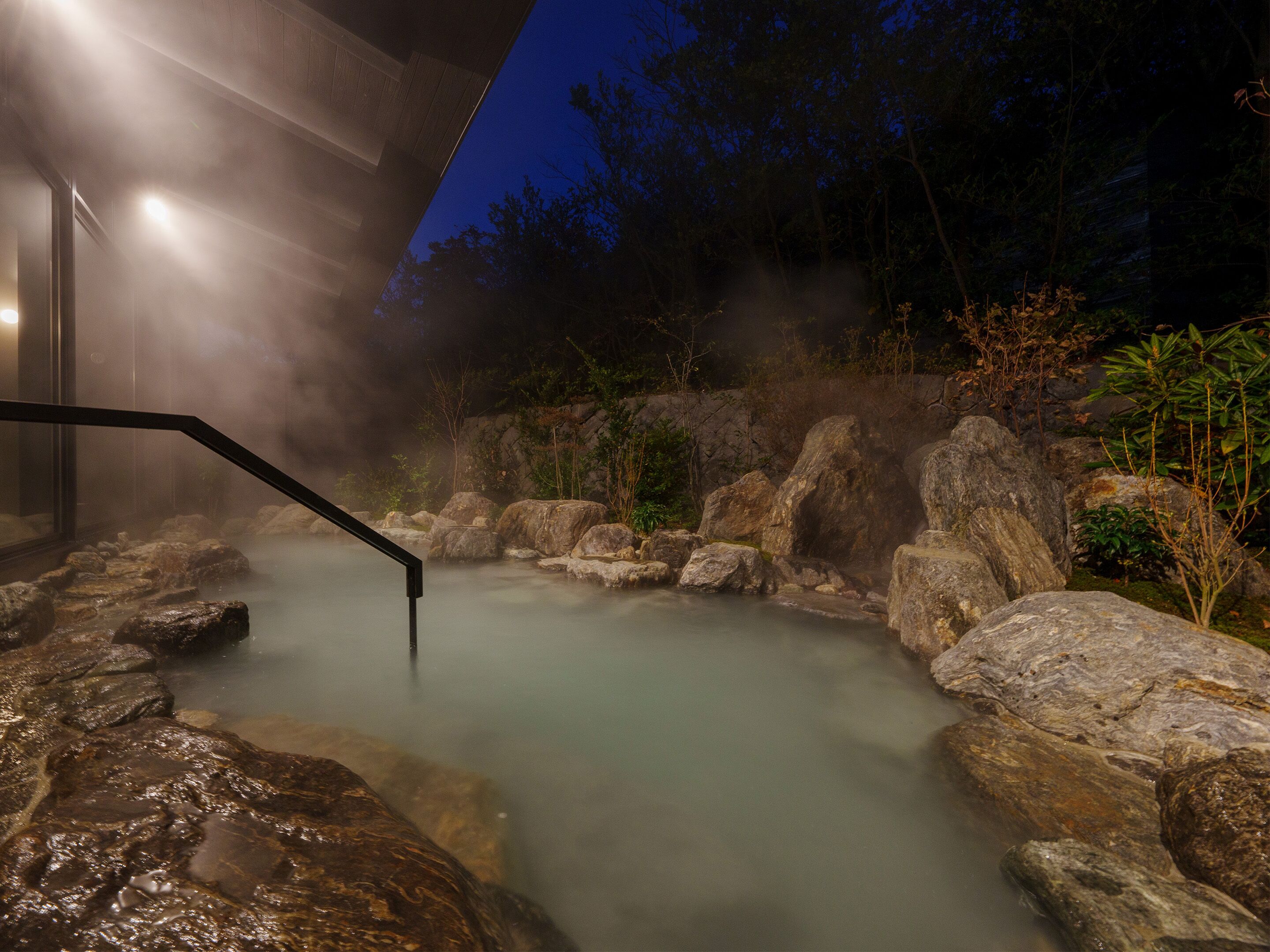 Un área de aguas termales con rocas y una escalera de madera.