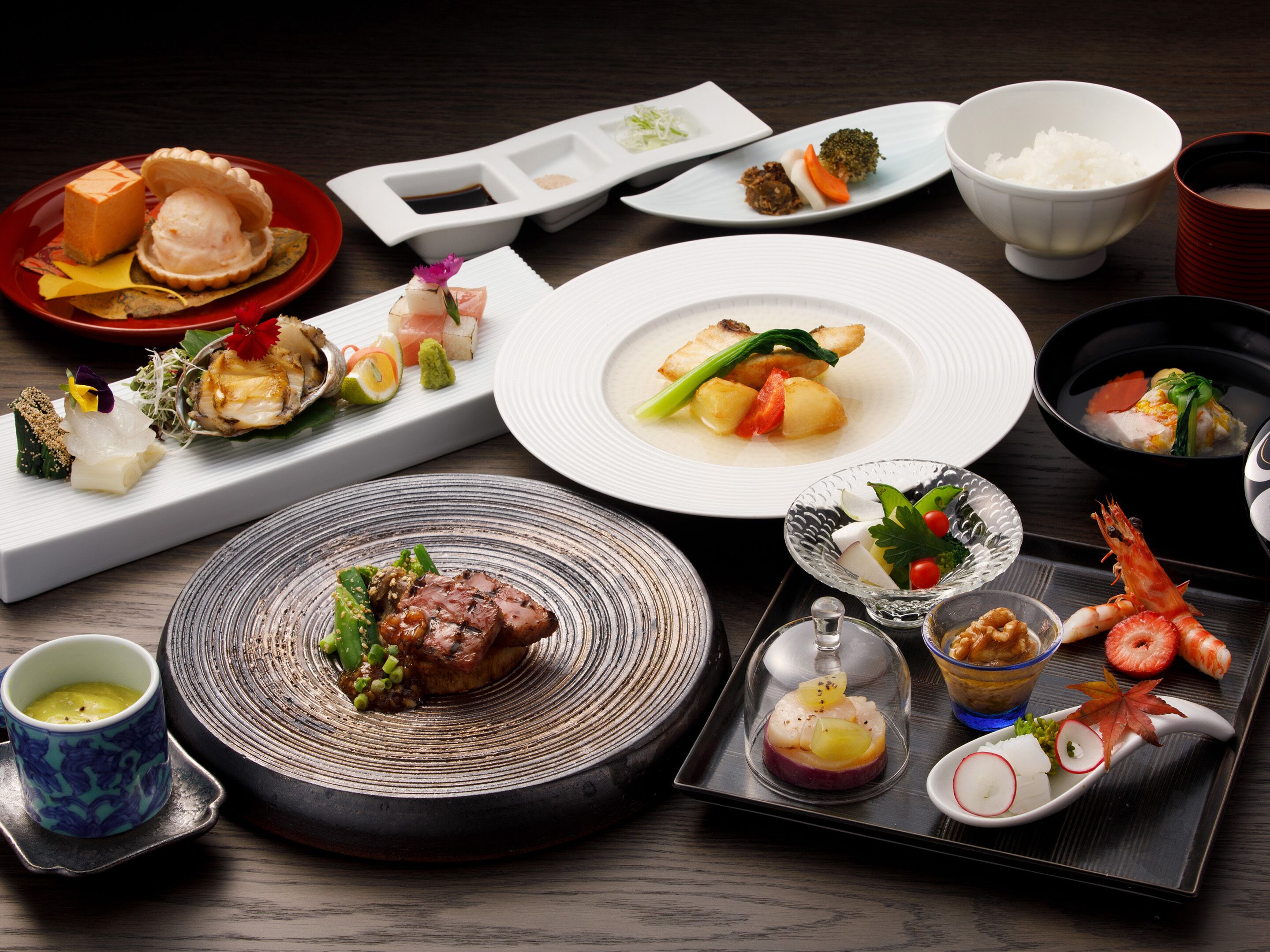 A variety of dishes on a table, including seafood, vegetables, and a meat dish, suggesting a diverse meal selection.
