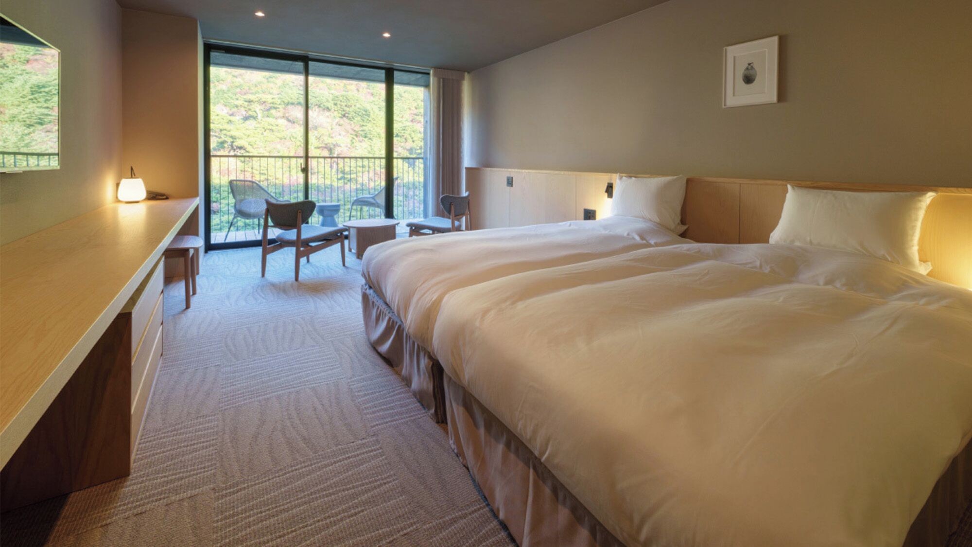 A hotel room with a large bed, a desk, a chair, and a balcony with a view.