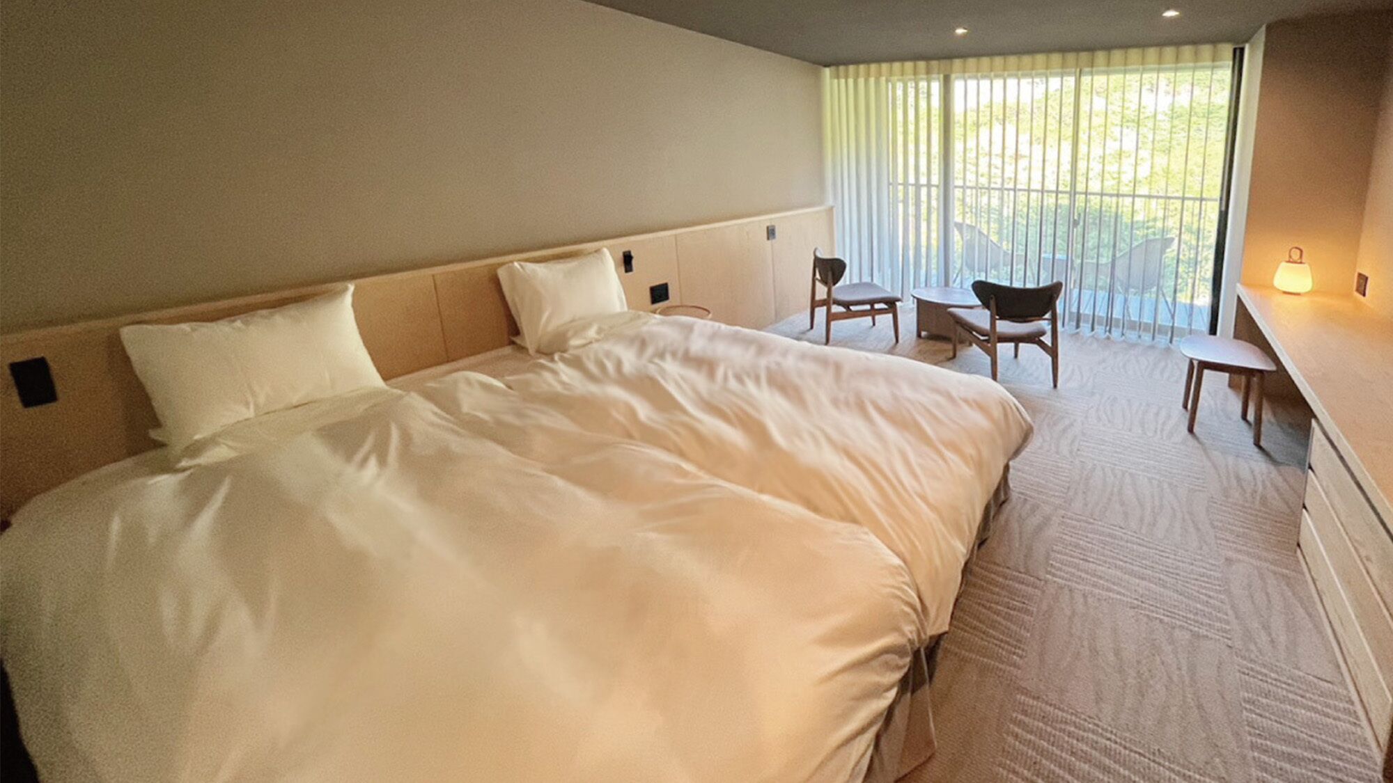 A hotel room with a large bed, a desk, and a chair.