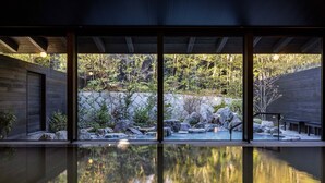 A modern building with large windows, a reflection pool, and a view of a rocky garden. - Unzen Miyazaki Ryokan (Unzen)