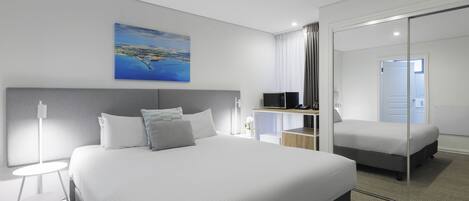 Una habitación de hotel moderna con una cama grande, un escritorio, un televisor y un cuadro de un paisaje.