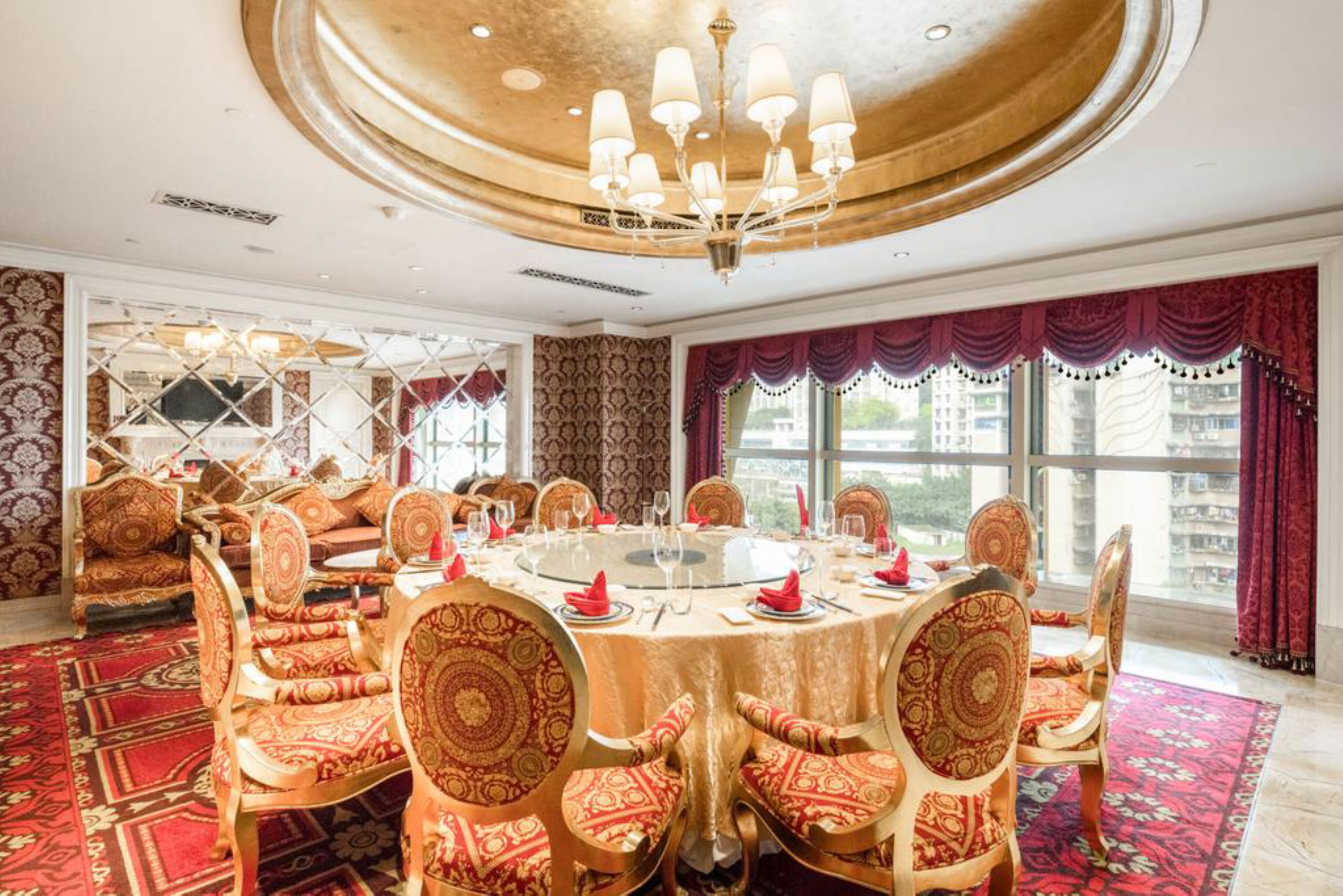 A dining area with a round table, chairs, and a chandelier.