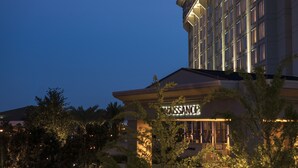 A hotel with a classical facade and illuminated signage.