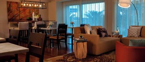 A modern living room with a sofa, chairs, a dining table, and a kitchen area.