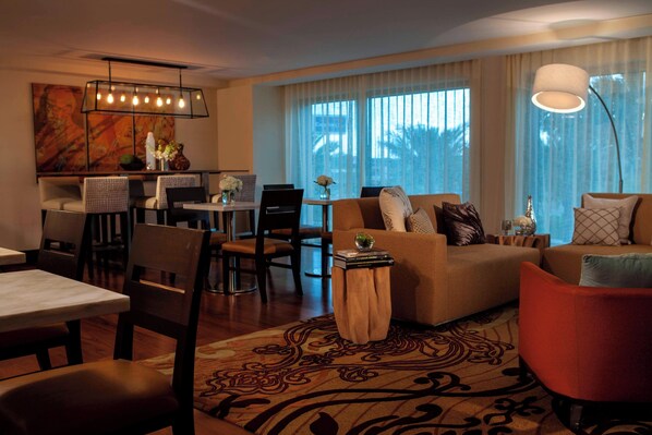 A modern living room with a sofa, chairs, a dining table, and a kitchen area.