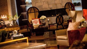 A cozy living room with a fireplace, comfortable seating, and decorative elements like flowers and books.