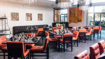 Un interior de restaurante moderno con asientos de cuero, candelabros y obras de arte en las paredes.