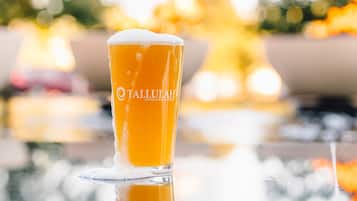 Una cerveza con espuma, etiquetada como "Tallulah Crafted Food and Wine Bar", sobre una superficie reflectante.