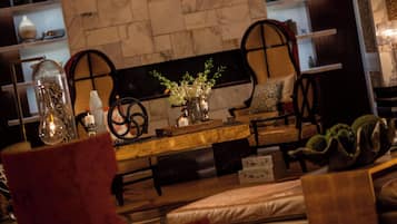 A cozy seating area with a wooden table, chairs, and a vase with flowers.