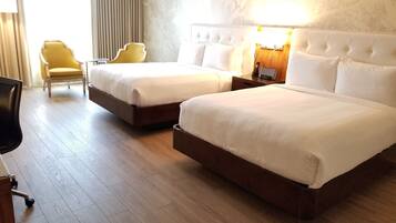 Una habitación de hotel con dos camas, un escritorio, una silla y una lámpara.