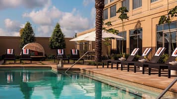 Una piscina al aire libre, sombrillas, sillones reclinables de piscina