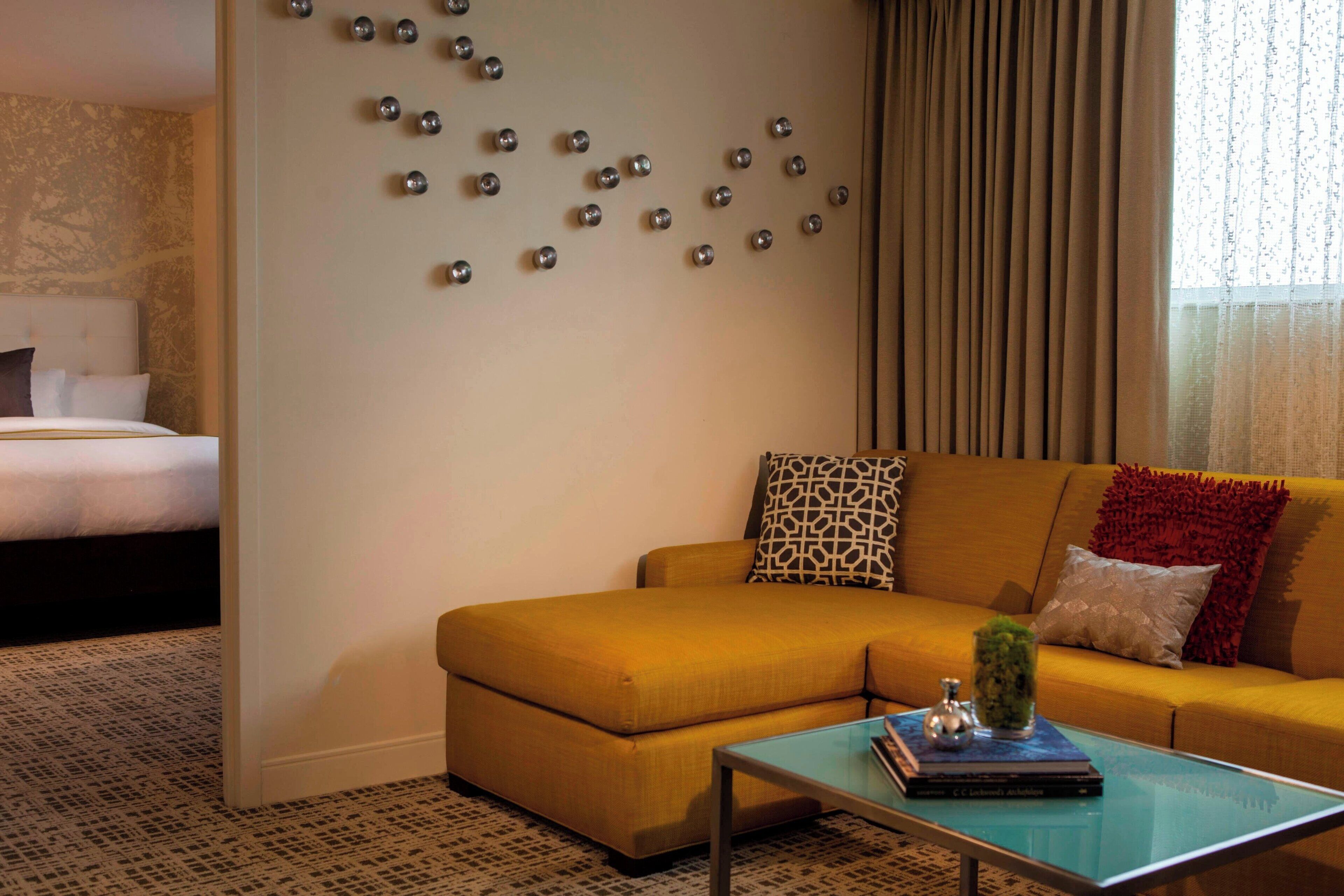 A living room with a sofa, a coffee table, and a wall with decorative metal spheres.