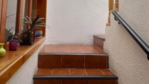 Un escalier avec des balustrades en bois, une décoration murale en forme de soleil et des plantes en pot sur le palier.