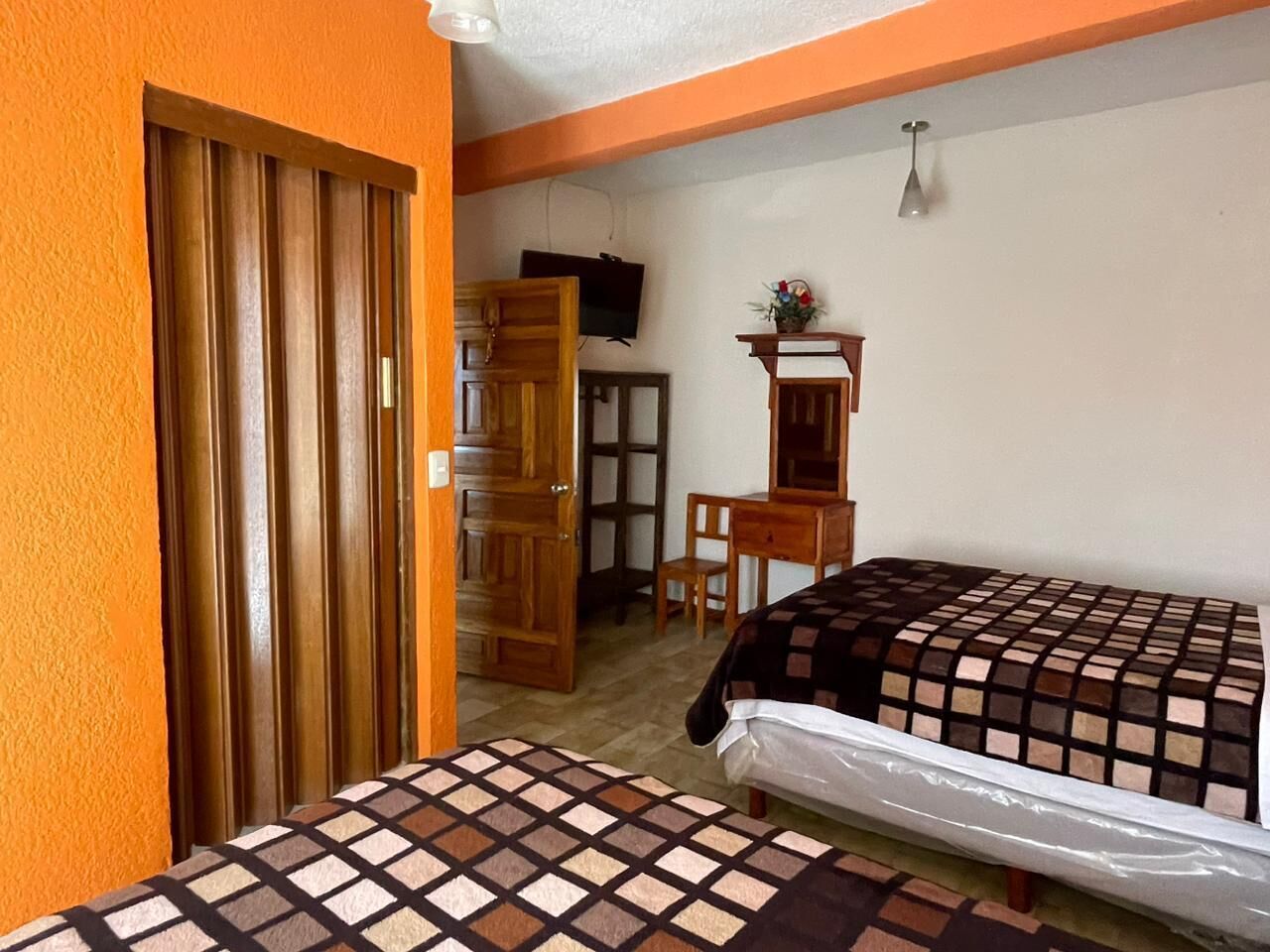Una habitación con dos camas, un armario de madera, un escritorio y una televisión.