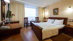 Une chambre d’hôtel avec un grand lit, un bureau, une chaise et une télévision.