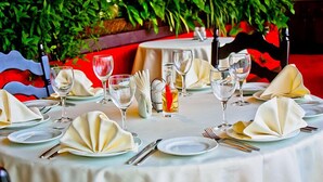Une table dressée pour le repas, avec des nappes blanches, des assiettes, des couverts et des verres.