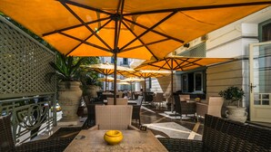 An outdoor seating area with wicker furniture and yellow umbrellas providing shade. - Majestic Hotel (Tunis)