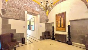 Una hall con pareti in pietra, un lampadario, un quadro e un pavimento piastrellato.