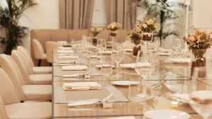 Une longue table à manger, agrémentée de chaises, de verres et de compositions florales.