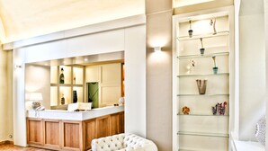 Un hall d’hôtel moderne comprenant un comptoir d’accueil, un espace salon et une étagère en verre où sont exposés des objets décoratifs.