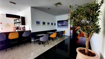 Um lobby de hotel moderno com área de bar, assentos e um vaso de plantas.
