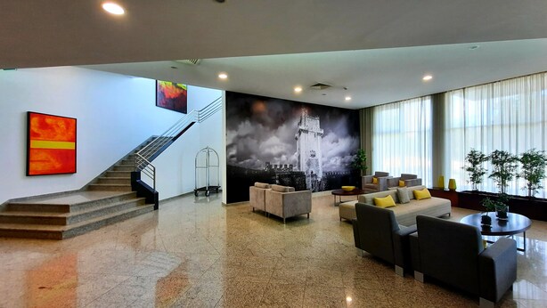 A modern lobby with a staircase, a large mural, and a seating area with sofas and a coffee table. - BejaParque Hotel (Beja)