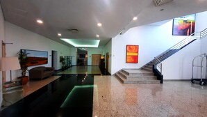 A modern lobby with a glass coffee table, a sofa, a potted plant, a staircase, and a wall-mounted artwork. - BejaParque Hotel (Beja)