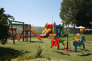 A playground with a slide, climbing structure, and horse-shaped swings.