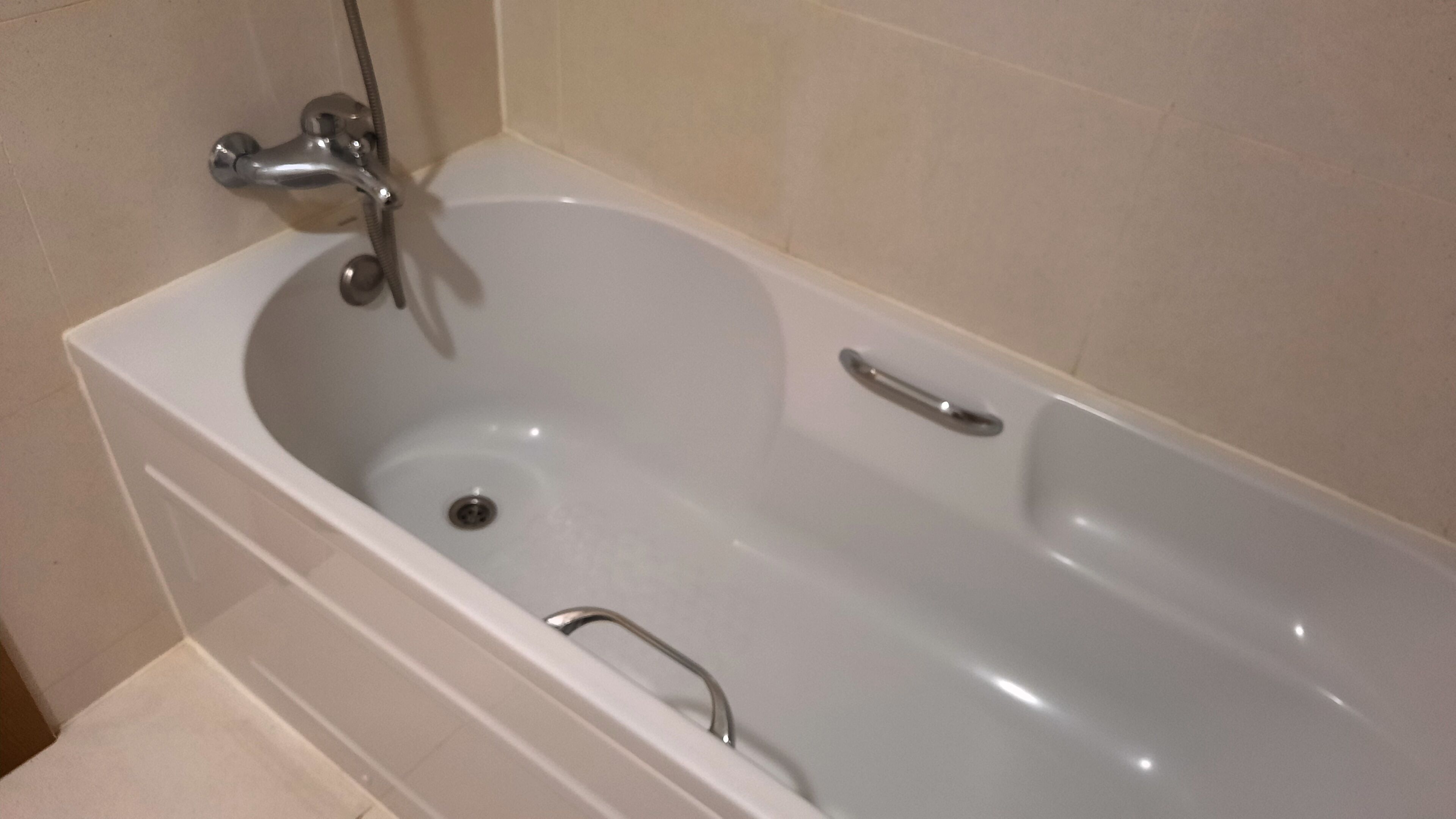 Una bañera blanca con un solo grifo y un cabezal de ducha de mano.