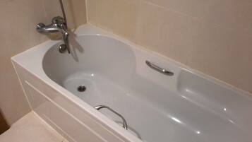 Una bañera blanca con un solo grifo y un cabezal de ducha de mano.