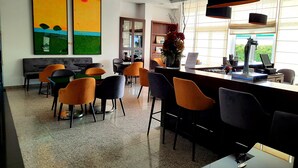 A modern hotel lobby with a bar area, seating, and artwork on the walls. - BejaParque Hotel (Beja)