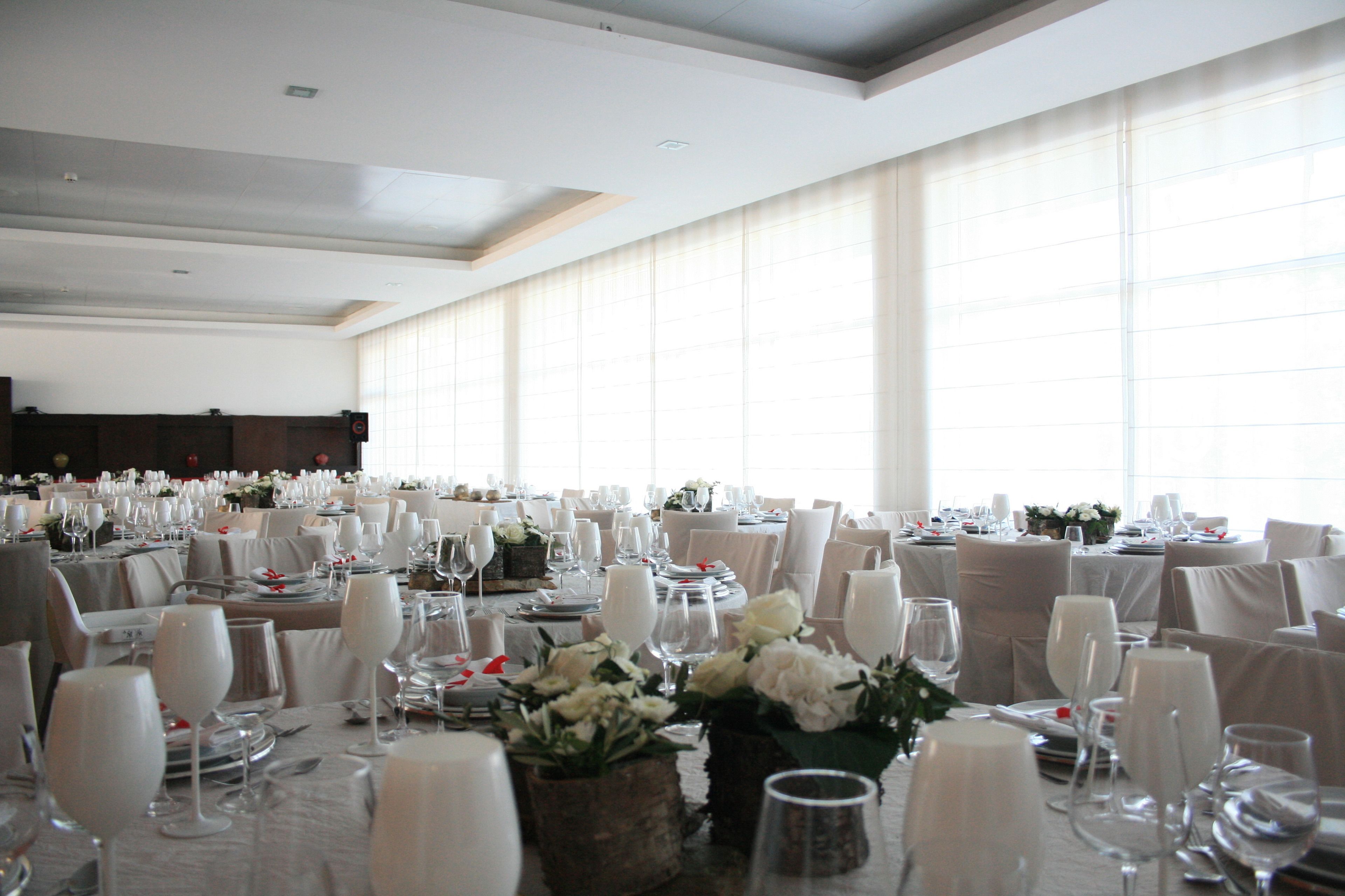 A banquet hall with round tables set for a formal event, featuring white tablecloths, chairs, and floral centerpieces.