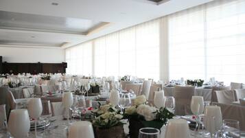 A banquet hall with round tables set for a formal event, featuring white tablecloths, chairs, and floral centerpieces.