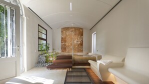 A modern interior with a sofa, a wooden bench, and a glass partition. - Hotel Il Villino (Santarcangelo di Romagna)