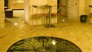 A spacious interior with a round glass table, two metal chairs, and stone arches. - Hotel Il Villino (Santarcangelo di Romagna)