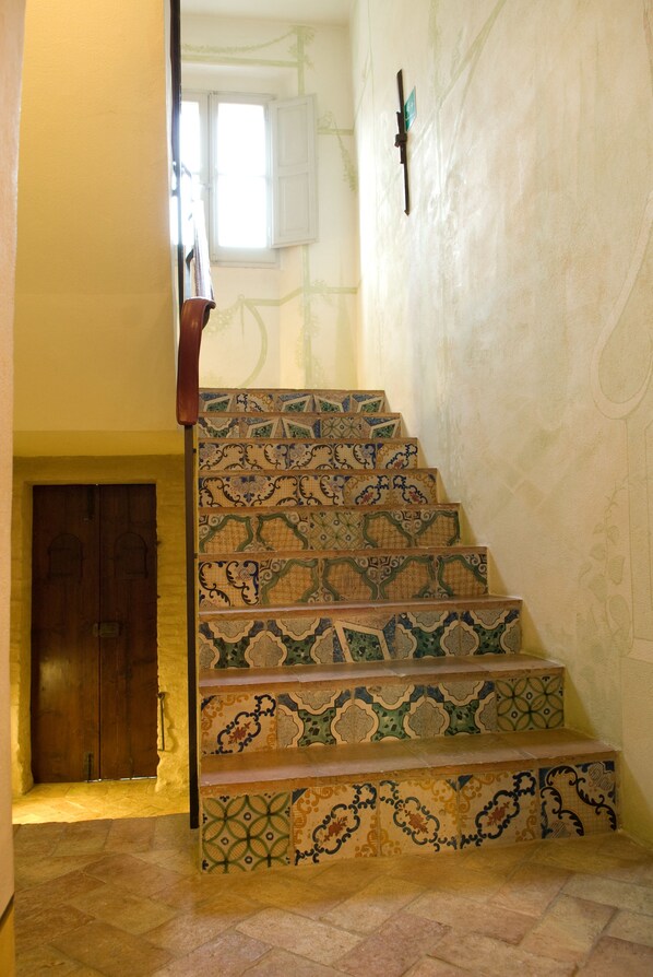 Una escalera con baldosas ornamentadas y con diseños, que conduce a una puerta de madera.