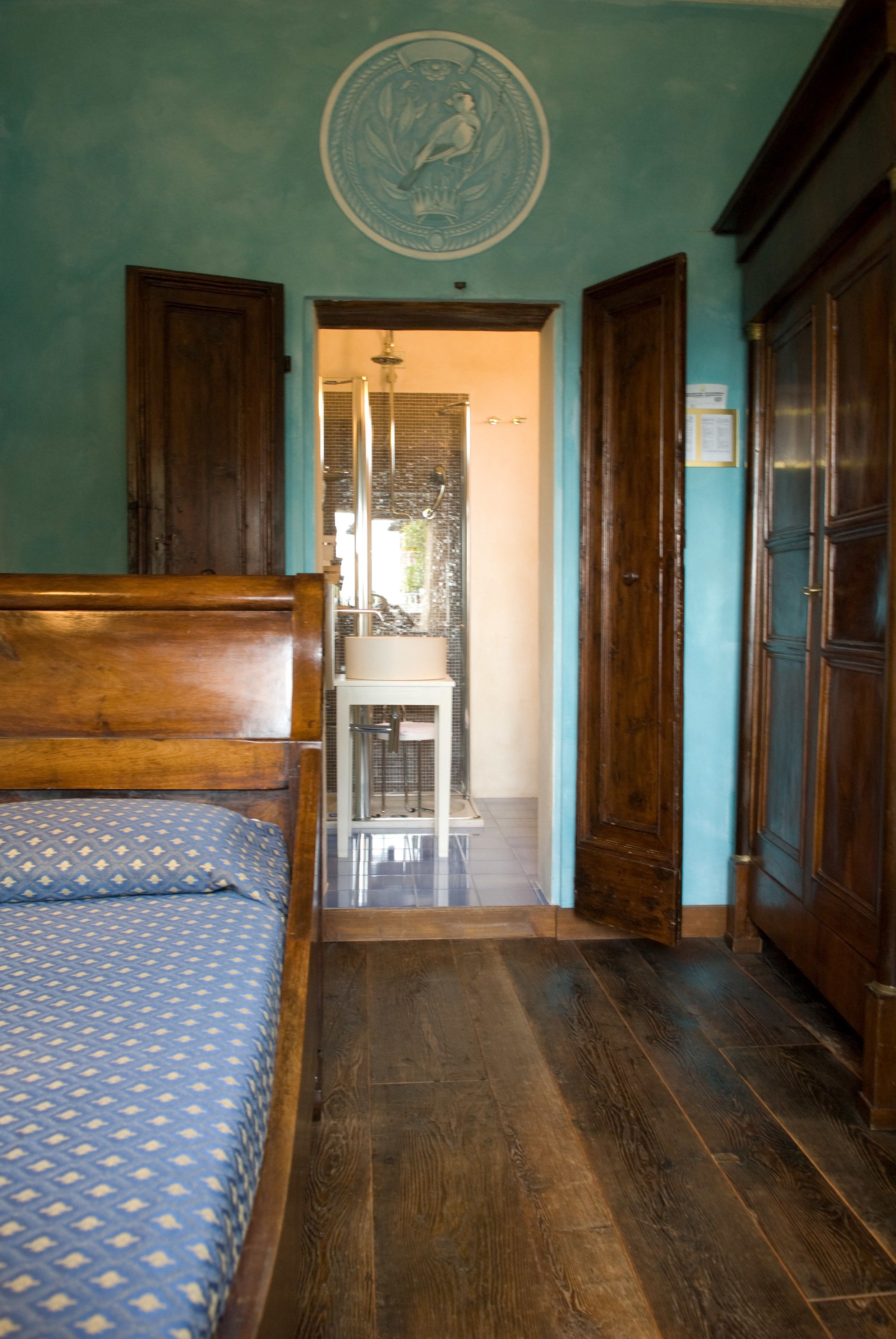 A bedroom with a wooden bed, a small table with a mirror, and a door leading to a bathroom.