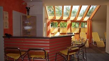 A restaurant with a red and white striped counter, yellow chairs, and a view through large windows.