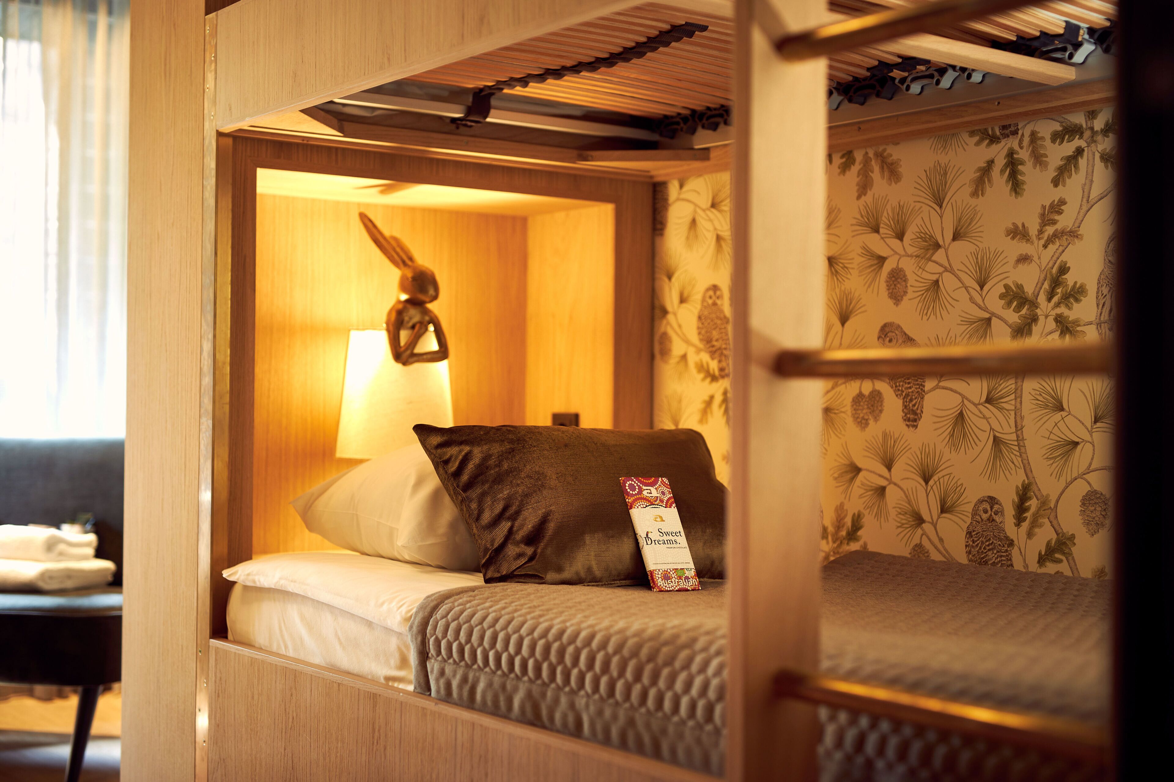 A bunk bed with a headboard, a bedside lamp, and a pillow with a tag.