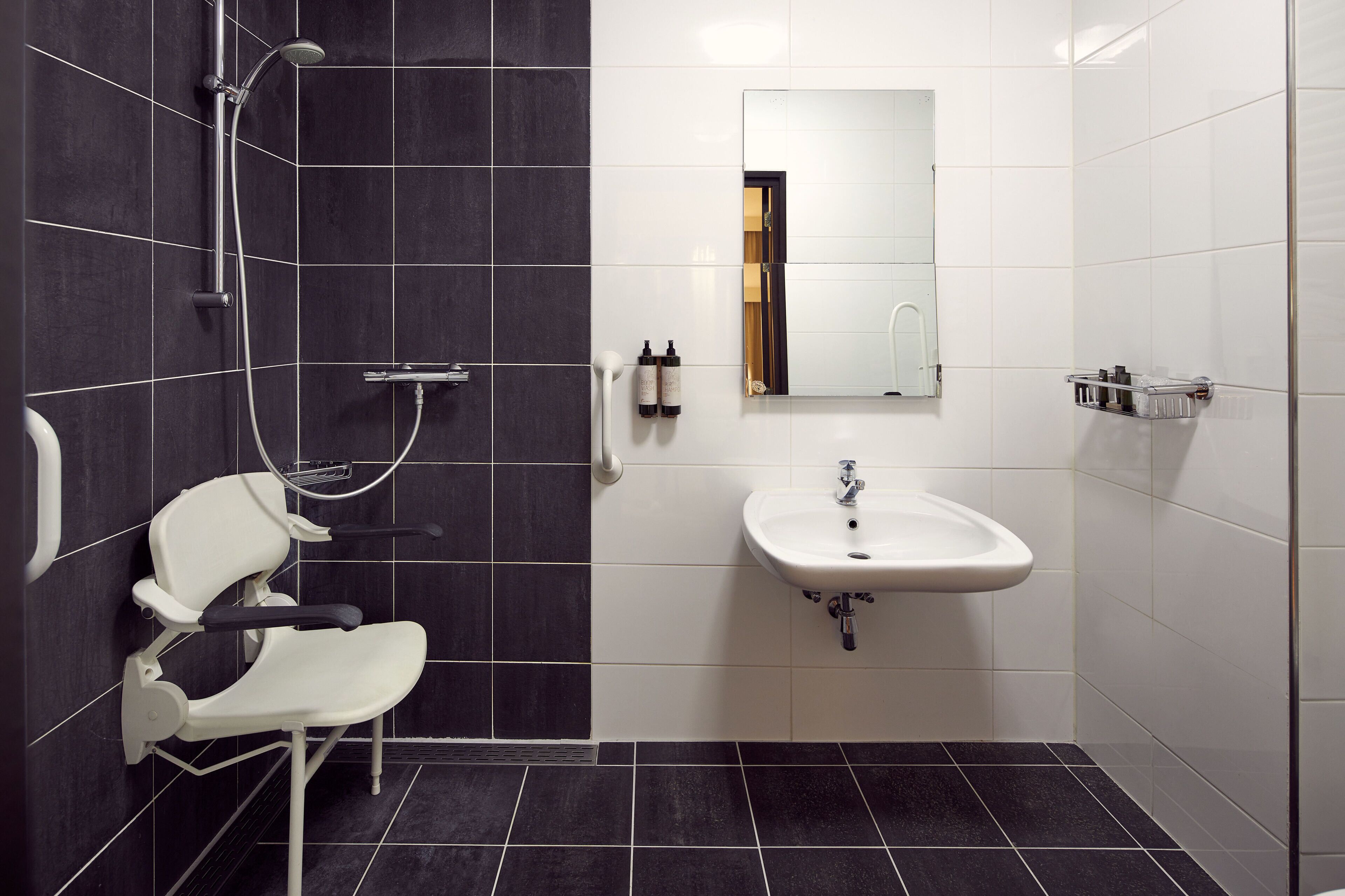 A modern bathroom with a shower, a sink, and a mirror.