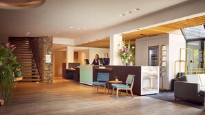A modern reception area with a wooden staircase, reception desk, seating area, and a glass display cabinet.