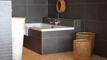 A modern bathroom with a bathtub, a toilet, and a large decorative vase.