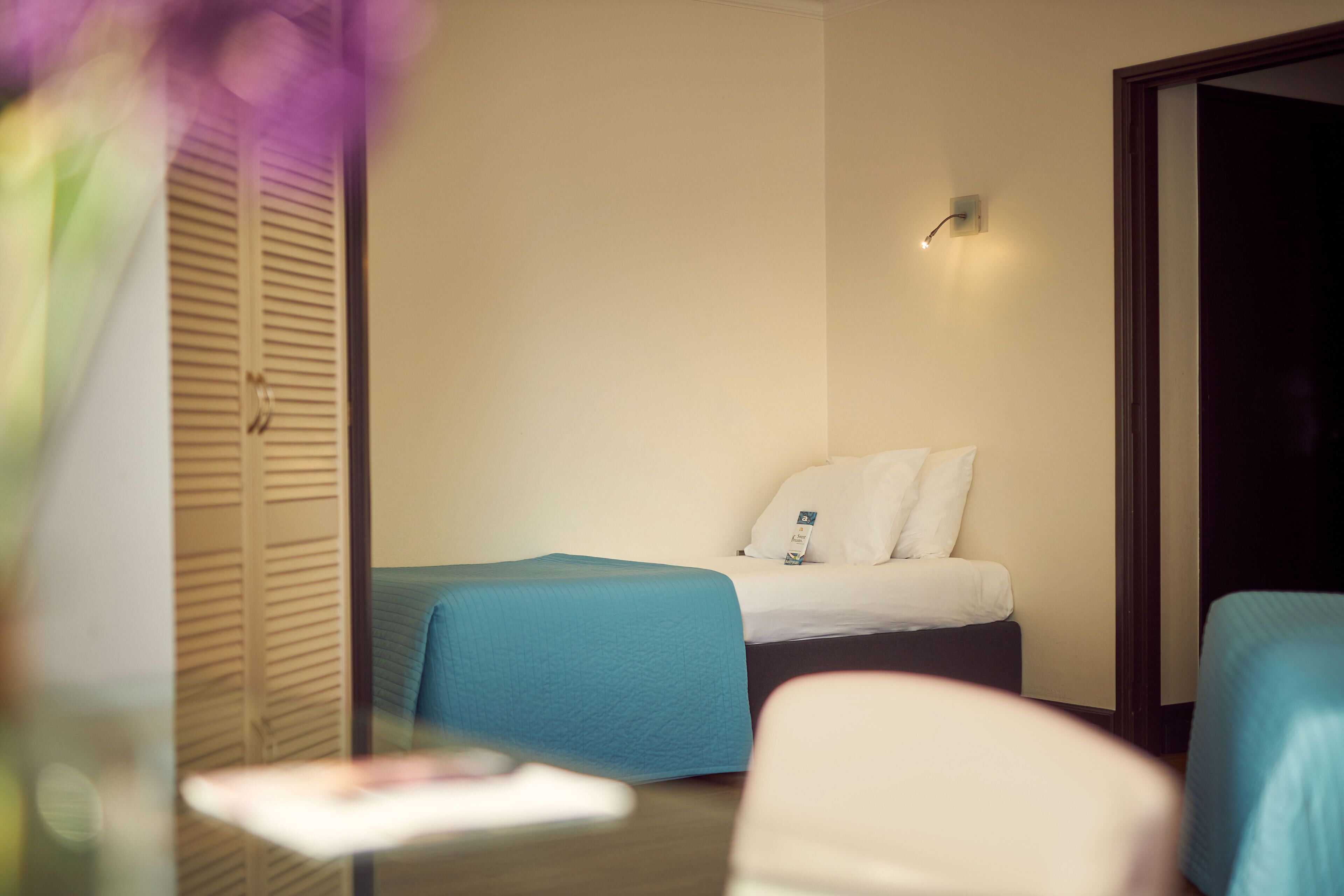 A hotel room with a bed, a bedside table, and a chair.