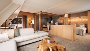 A modern hotel room with a sofa, wooden coffee table, and a bed with a headboard.
